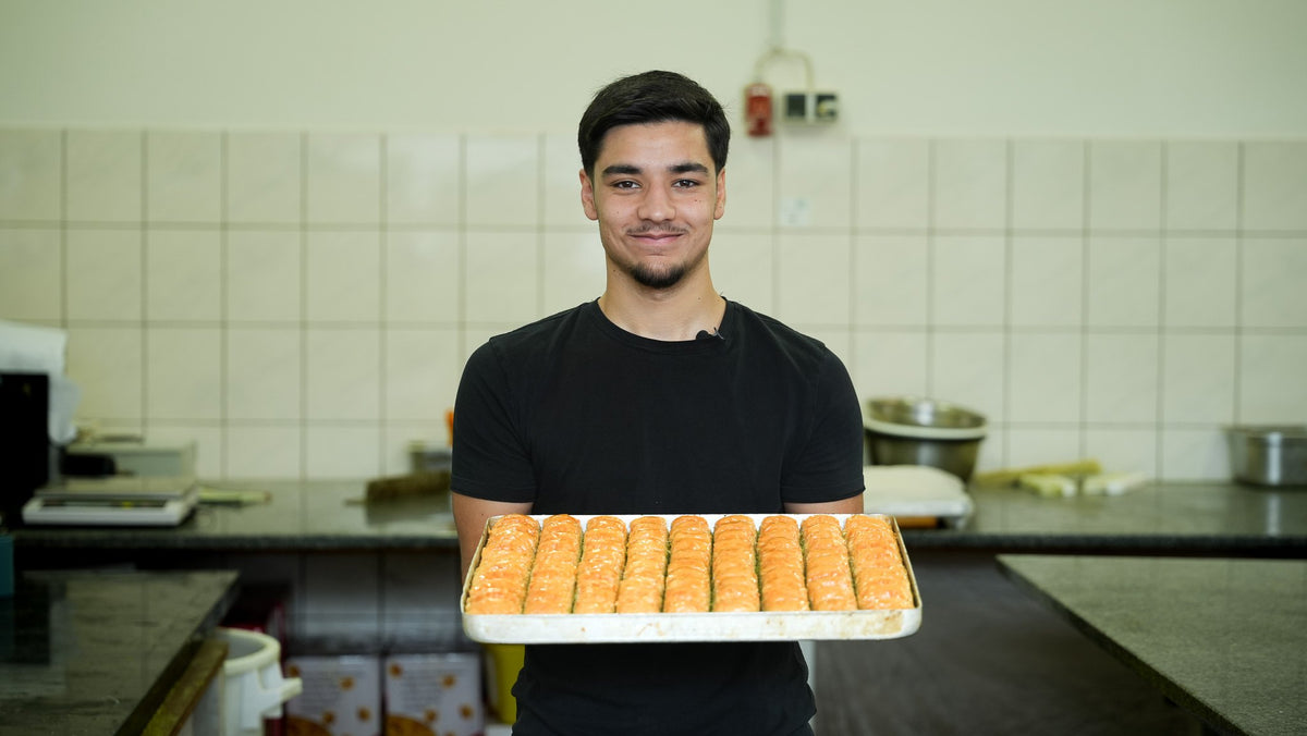 Back-Lava Mitarbeiter hält ein frisches Blech Baklava in der Hamburger Backstube